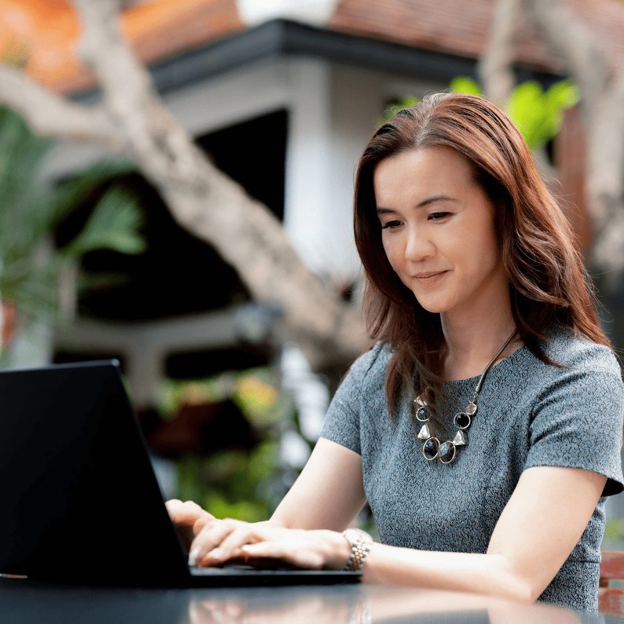 asian woman working on her laptop outside