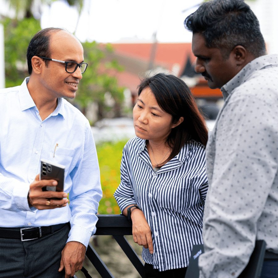 a woman and two men looking at a phone