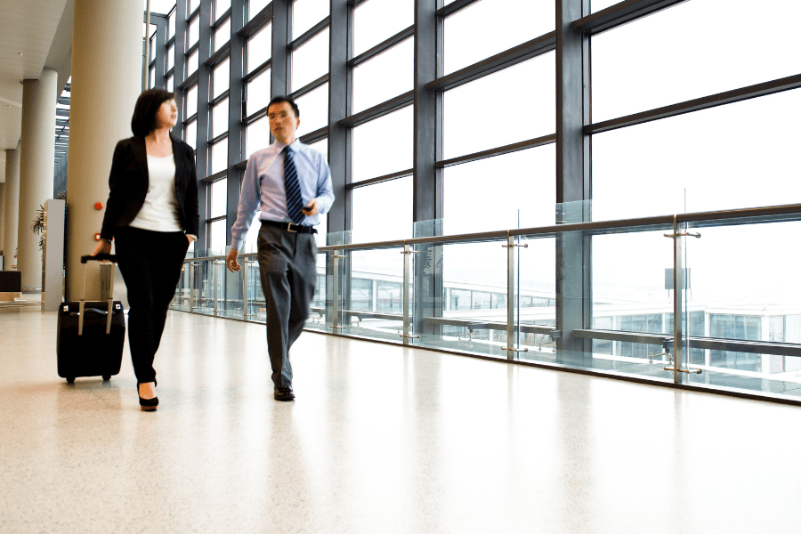 businesswoman and businessman walking through an airport corridor