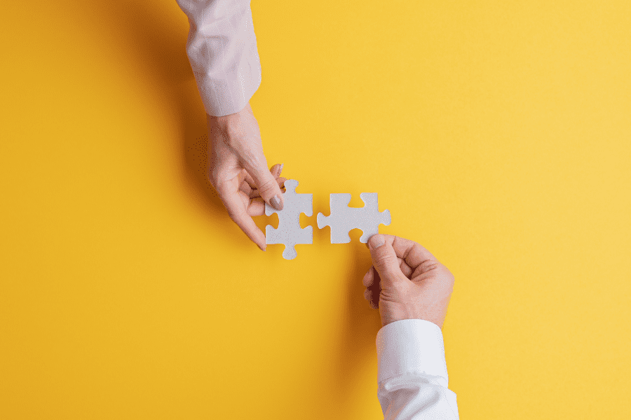 top view of male and female hands joining two matching puzzle pieces together