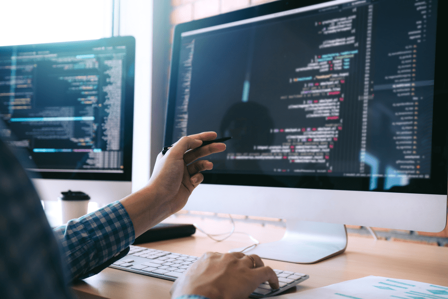 software developer holding a pen pointing to a computer screen