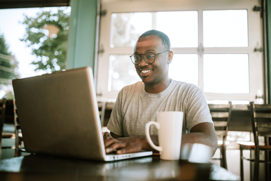 a young African American works remotely on his laptop