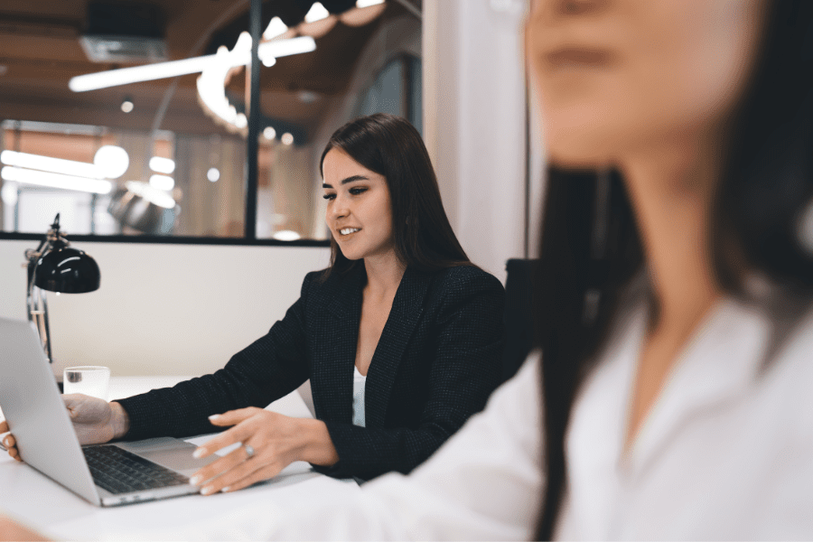 Female Independent Contractor working on a laptop besides another employee