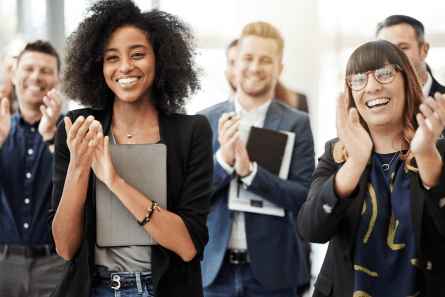 a group of Latin American employees clapping and smiling