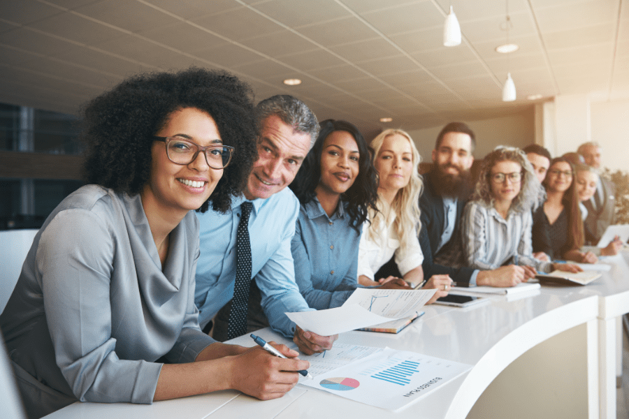 Group of newly hired professionals smiling for a picture inside office during a meeting